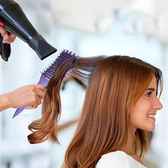 femme faisant brushing avec brosse cheveux boucles